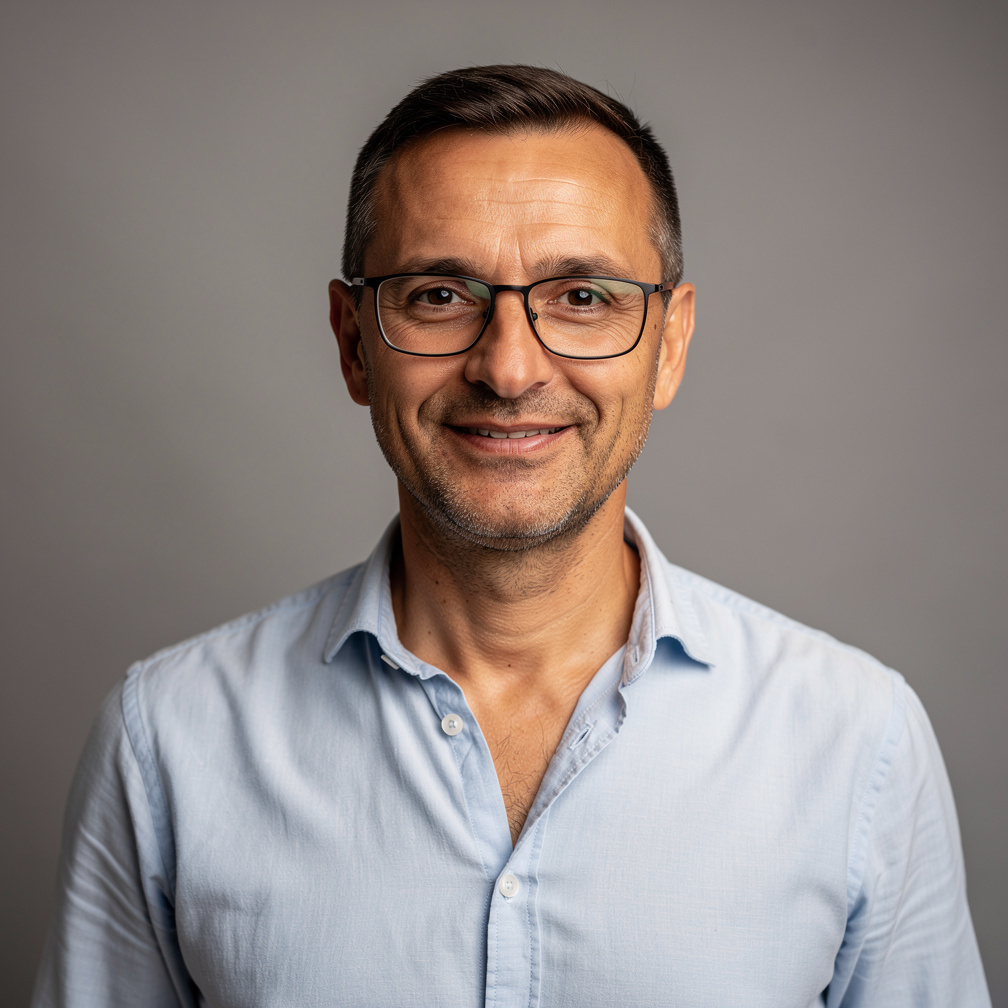 Studio portrait of a middle-aged Croatian man with short dark hair and glasses, smiling, neutral background